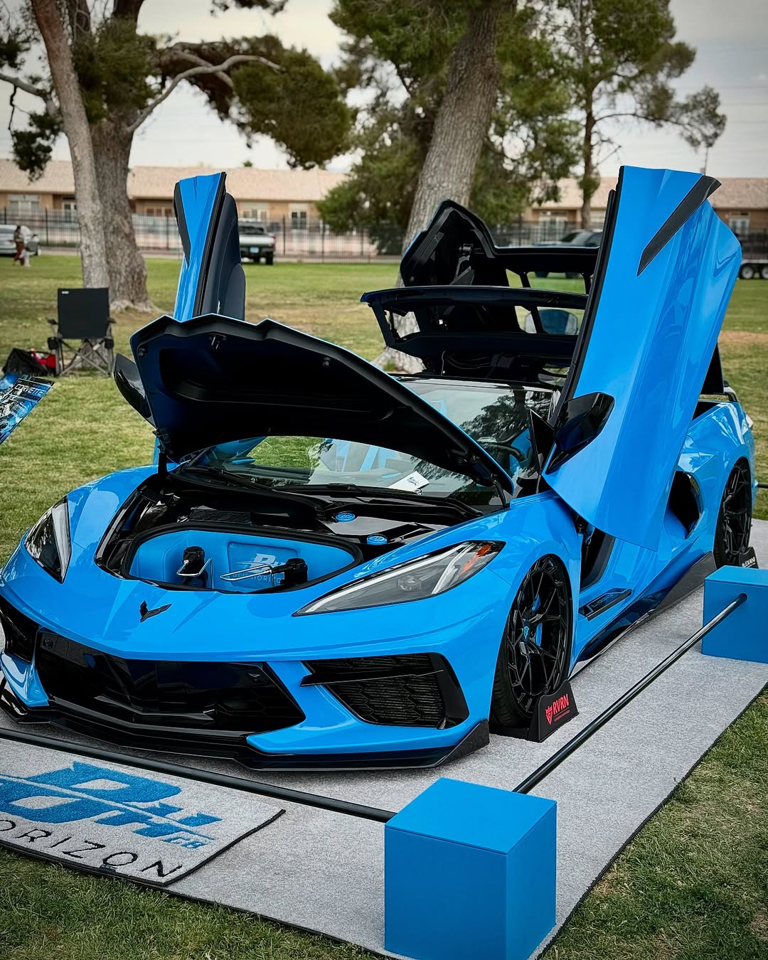 Custom blue Corvette C8 with open doors on display, showcasing aftermarket modifications and design.
