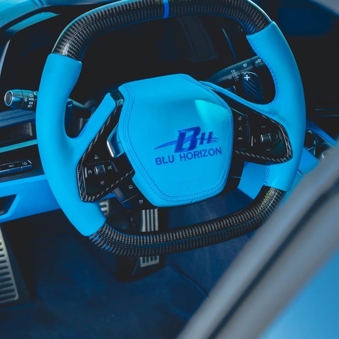 Custom blue steering wheel with carbon fiber details in a luxury car interior.
