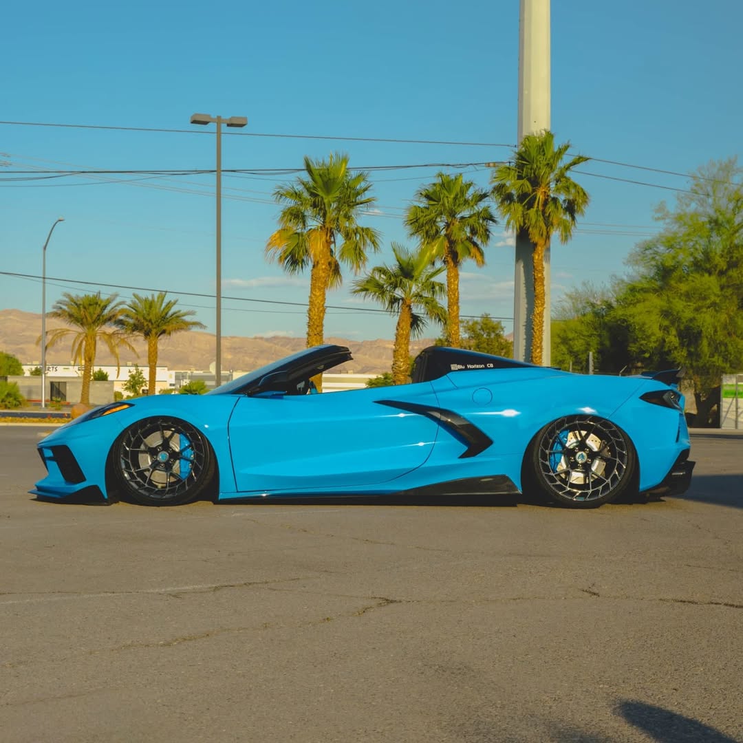 Blue Corvette C8 convertible featuring custom forged carbon flash wheels and a sleek design, parked on a sunny street.