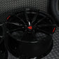 Custom forged black Corvette C6 Z06 wheels with concave design and red accents on textured background.