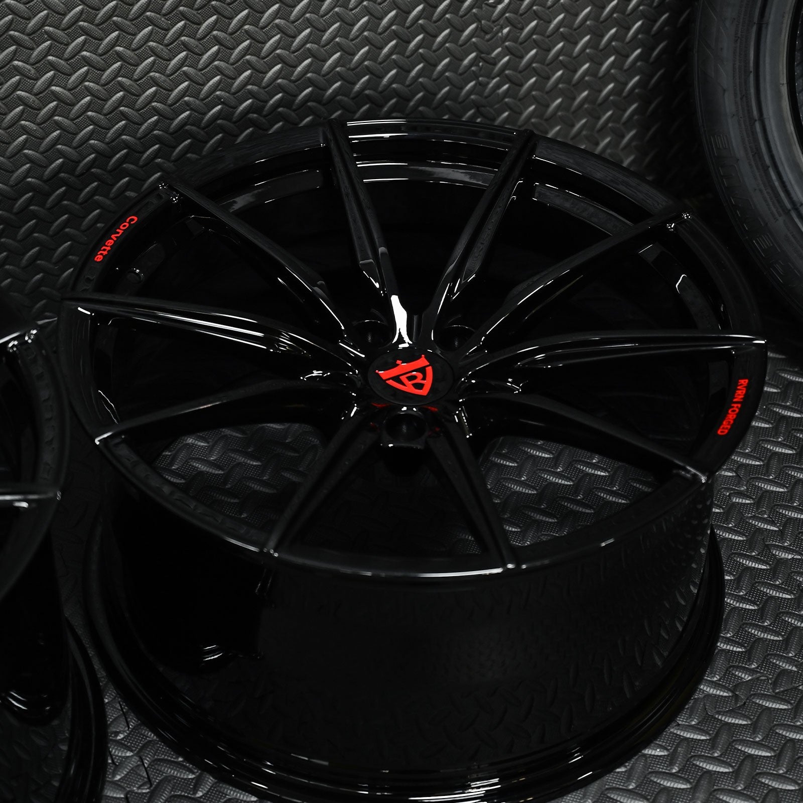 Custom forged black Corvette C6 Z06 wheels with concave design and red accents on textured background.