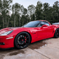 Red Corvette C6 Z06 parked on a driveway, featuring custom black forged rims for enhanced style and performance.