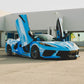 Blue Corvette C8 with custom aftermarket wheels and butterfly doors in a modern outdoor setting.