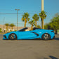 Blue Corvette C8 convertible featuring custom forged carbon flash wheels and a sleek design, parked on a sunny street.